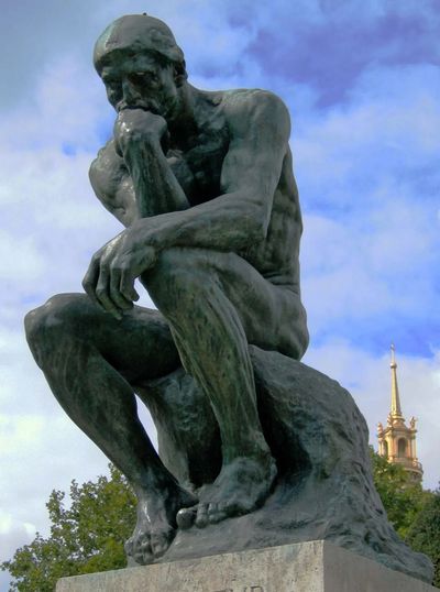 The Thinker statue by Auguste Rodin in a contemplative pose.