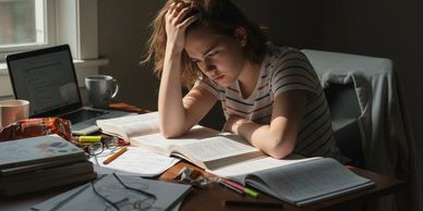 Stressed woman studying with books and laptop.