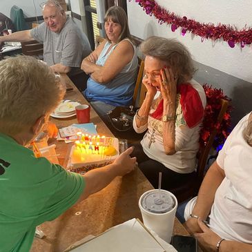 Woman surprised by a birthday cake with family at Moe's Country Kitchen.