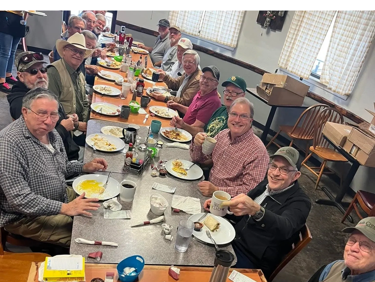 Group of men enjoying breakfast together at a long dining table.