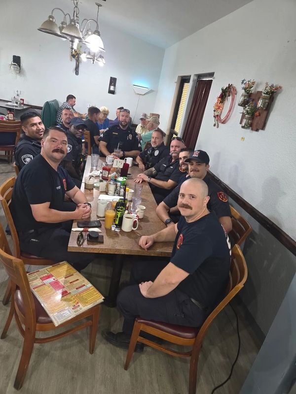 Group of emergency responders gathered around a long dining table in a restaurant.