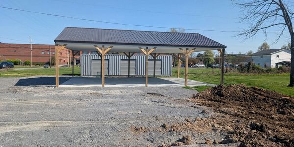 Newly constructed metal pavilion with a gravel ground and clear blue sky.