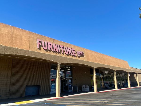 Exterior view of Furniture Now store under a clear blue sky.