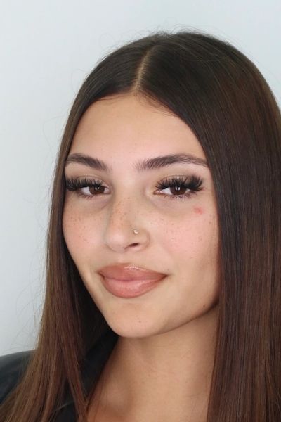 Young woman with long straight hair and nose piercing.