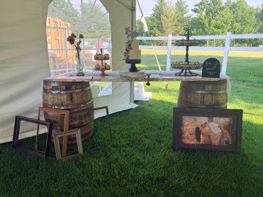Rustic outdoor table setup with barrels and framed photo.