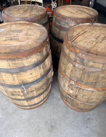 Four large wooden barrels on a concrete floor.