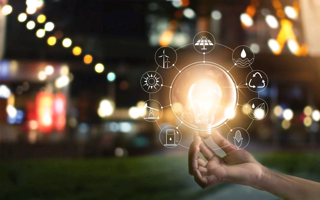 Hand holding glowing light bulb with energy icons.