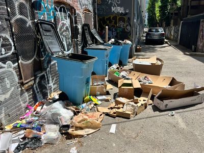 Trash and garbage on the ground promoting rat activity out back of apartment building in Boston's Ba