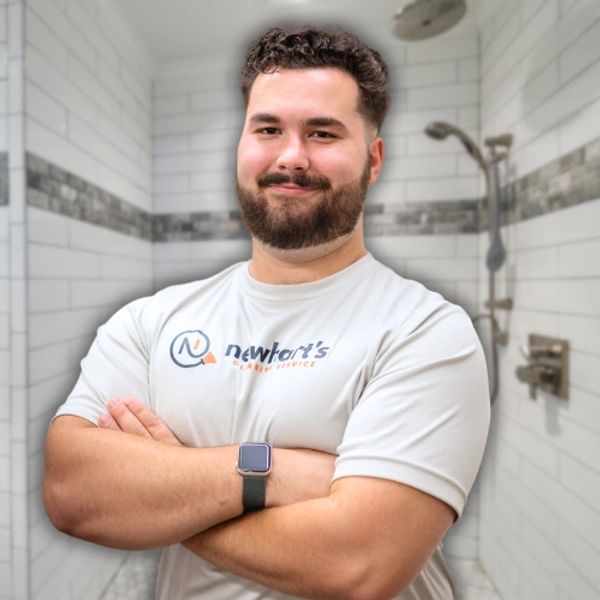 Man in white shirt stands confidently in a bathroom.