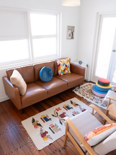 Cozy living room with a brown leather sofa and colorful cushions.