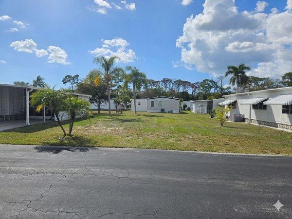Sunny day in a mobile home park with palm trees and clear blue sky.