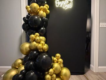 Black and gold balloon decoration with 'Congrats Grad' sign.