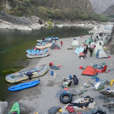 Camping and boating by a riverside with tents and rafts.