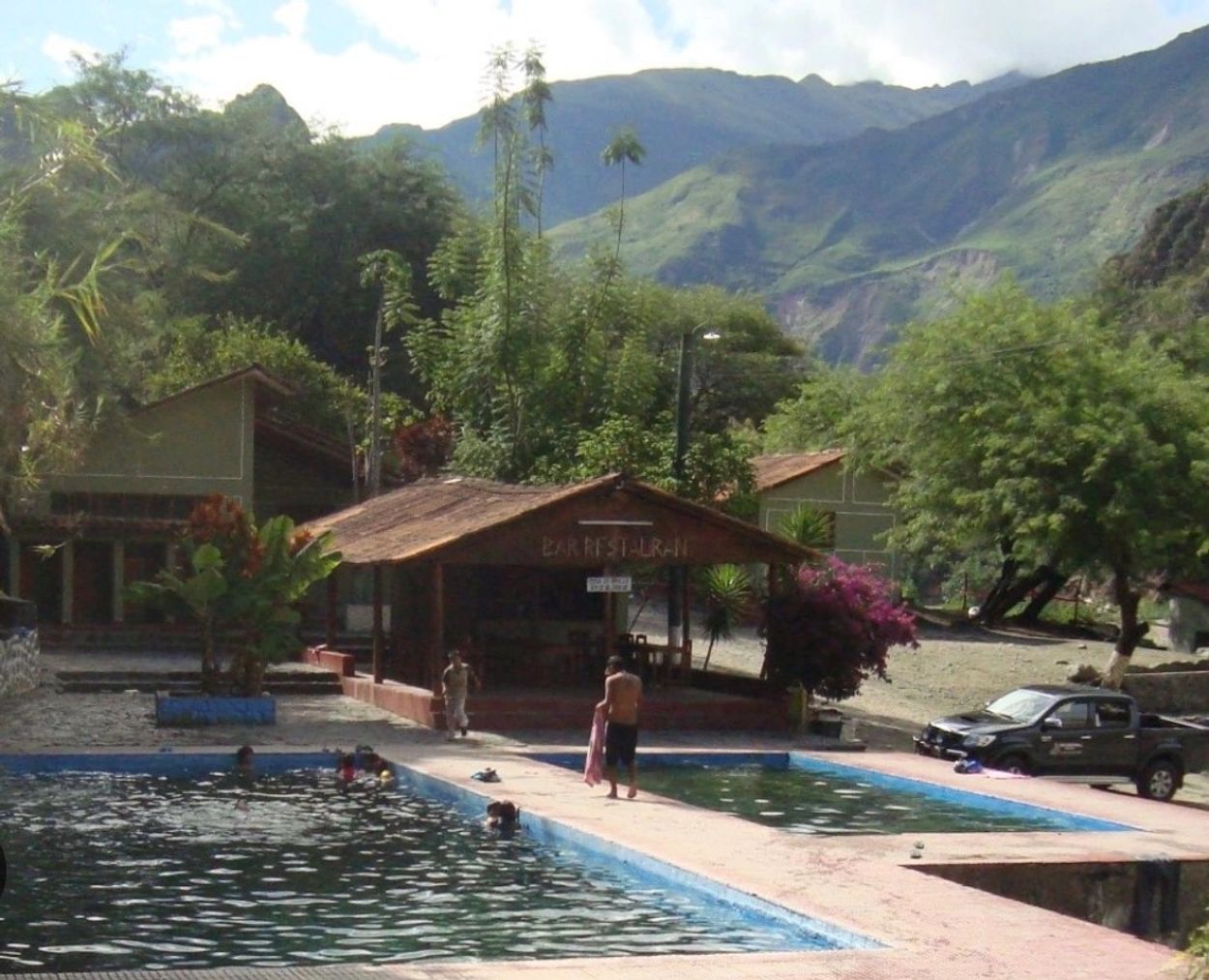 People enjoying a pool in a mountainous area.
