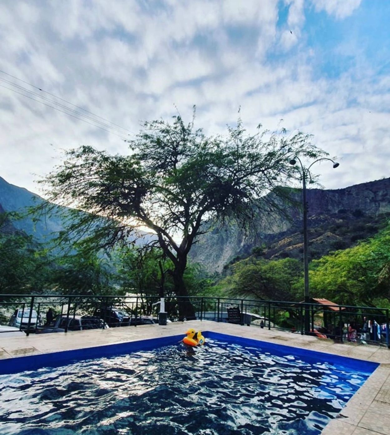 Outdoor pool with mountainous backdrop and cloudy sky.