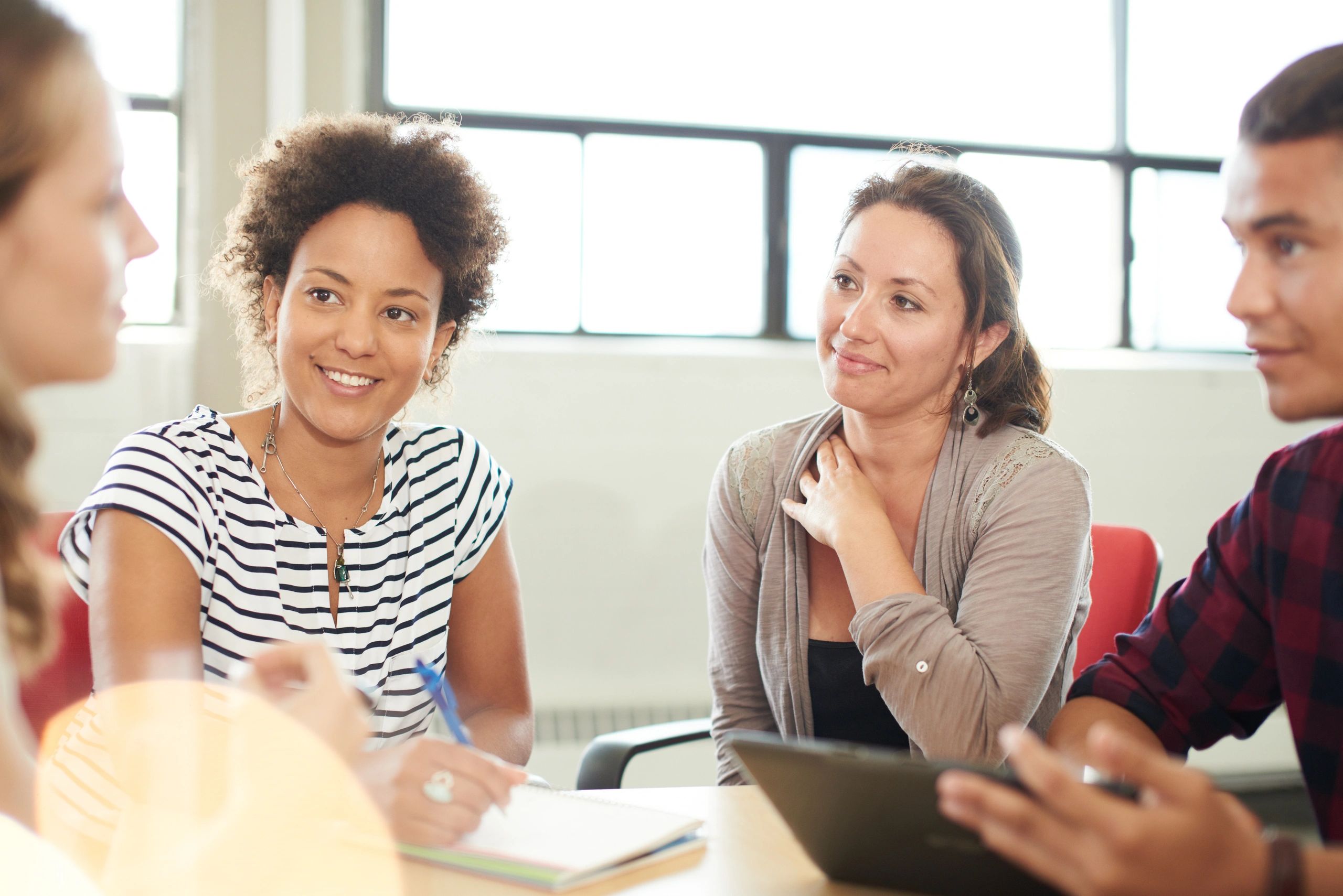 Young adults engaged in a friendly group discussion indoors.