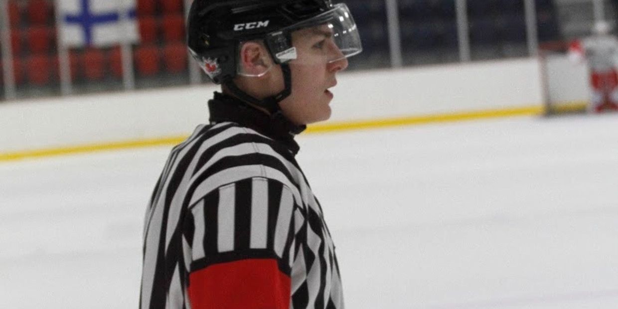 Hockey referee on ice rink in profile view.