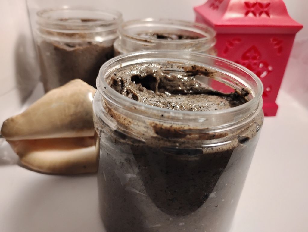 Jars of homemade scrub with a seashell and decorative red lantern.