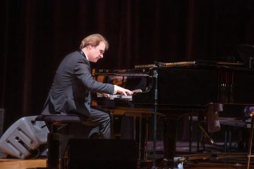 Musician playing piano on stage.