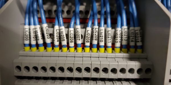 Blue wires with labeled tags connected in an electrical panel.