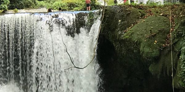 A massive multi-tiered waterfall in a lush tropical forest.