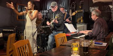 A lively band performs in a cozy, dimly lit bar with wooden furniture.
