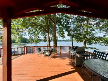 Spacious wooden deck with lake view and outdoor furniture.