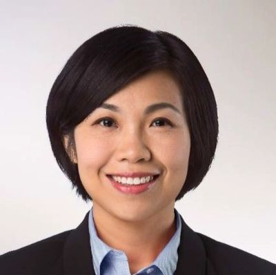 Professional woman smiling in business attire against a plain background.