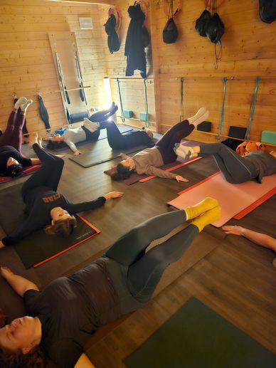 Group doing leg exercises on mats in a wooden room.