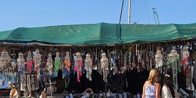 Outdoor market stall with colorful hanging decorations and visitors.
