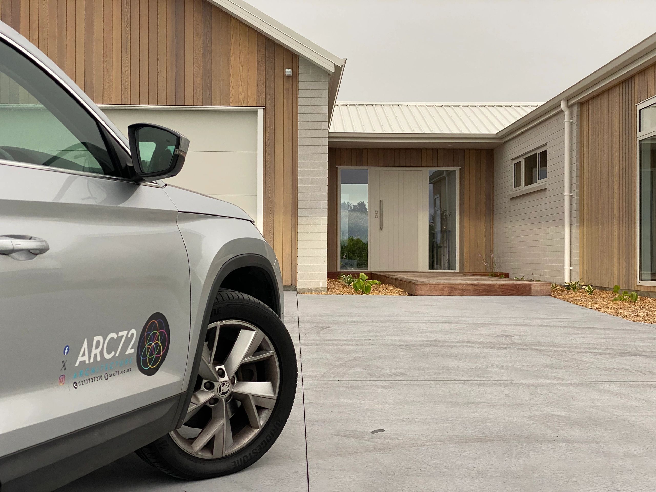 Modern house entrance with a parked ARC72 branded car in front.