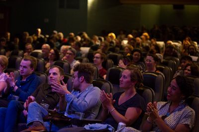 Audience clapping in a theater or auditorium.