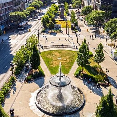 A city park with a central fountain and surrounding greenery.