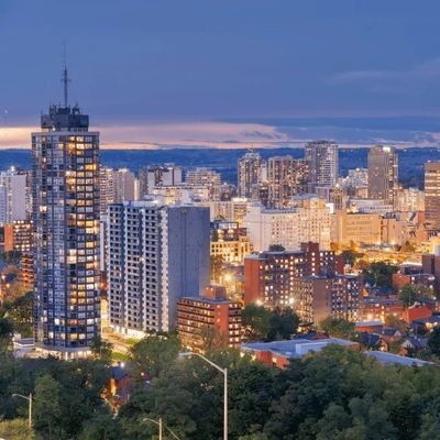 City skyline at dusk with illuminated buildings and a clear sky.