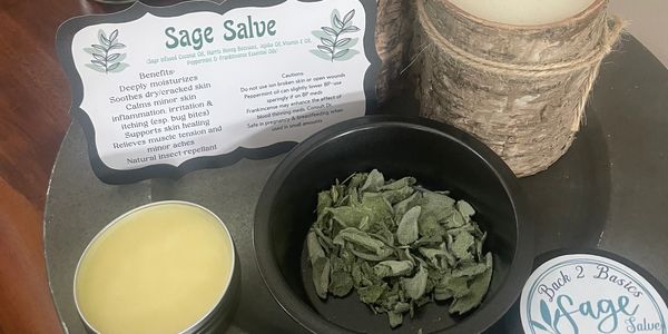 Natural sage salve with dried sage, candles, and informational card on a tray.