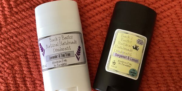 Two sticks of natural handmade deodorant on a textured orange surface.