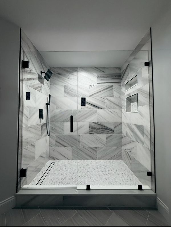 Modern walk-in shower with marble tiles and glass enclosure. Home remodeling project in Tampa Bay