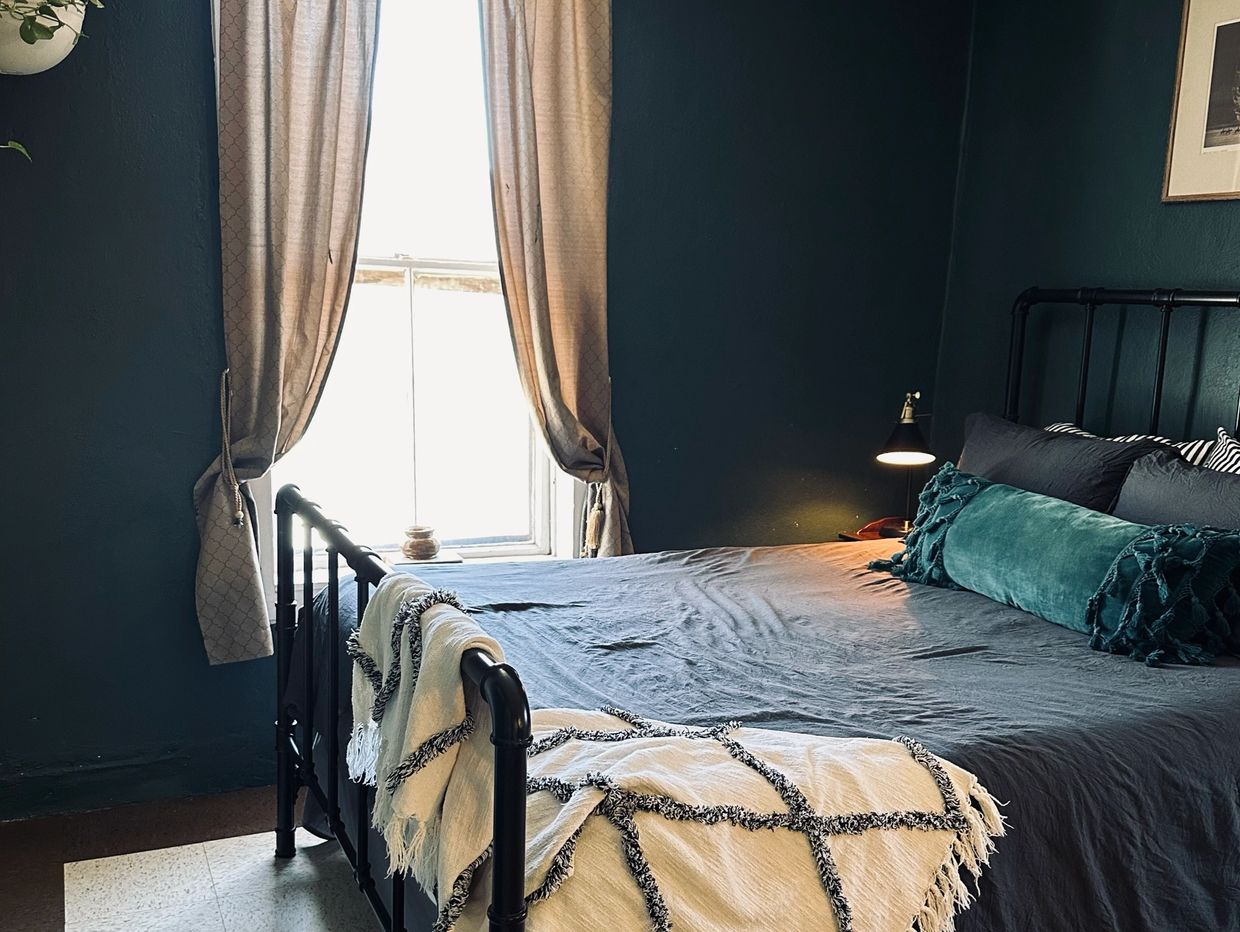 Cozy bedroom with dark walls, a black metal bed frame, and a soft throw blanket.