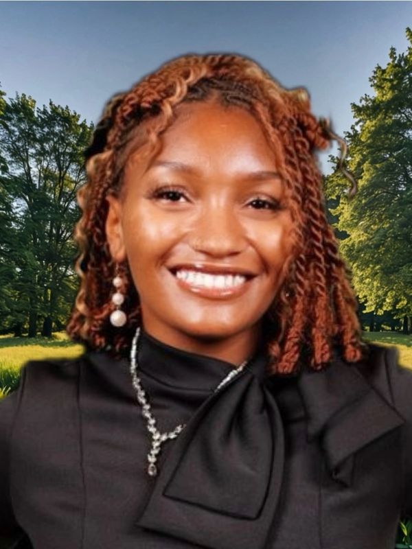 Smiling woman with braided hair wearing a black outfit and jewelry outdoors.