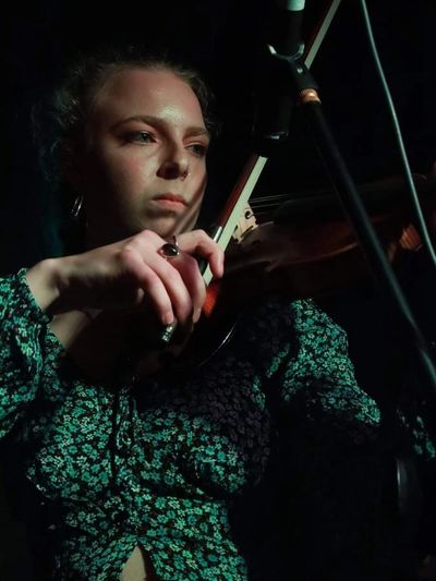 Nicola is playing her violin and looking down towards the scroll