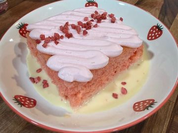 Slice of pink cake with cream and sprinkles.