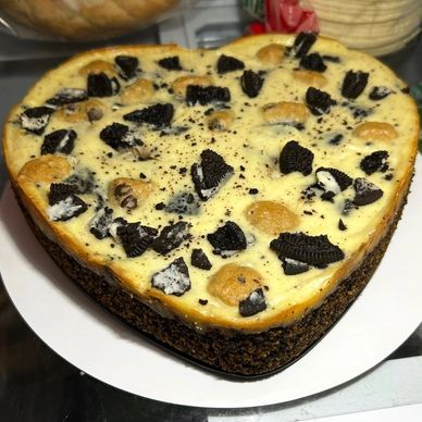 Heart-shaped Oreo and cookie cheesecake on a white plate.