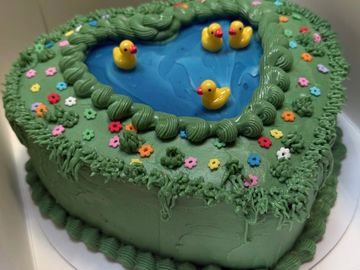 Heart-shaped duck pond cake with rubber ducks.