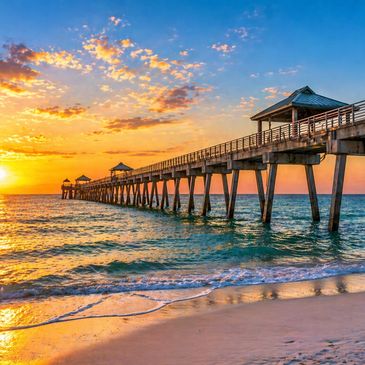 Sunset over a wooden pier extending into the ocean.