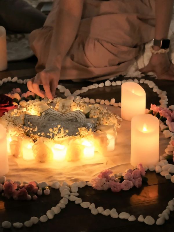 A person arranging candles and flowers in a circle during a ritual.
