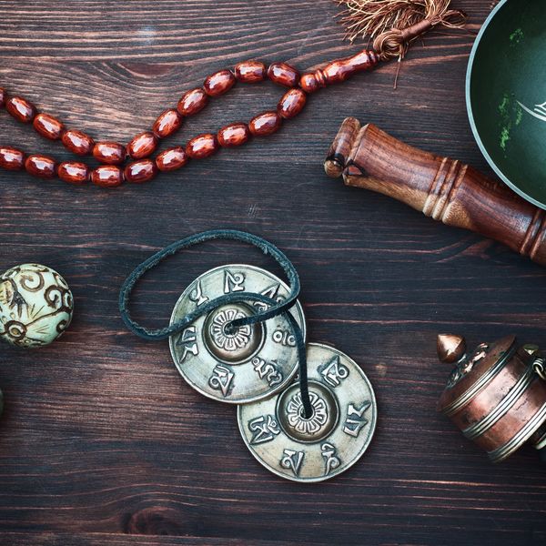 Meditation-related items on a wooden surface, including prayer beads, a singing bowl, and cymbals. 