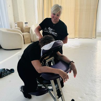 A person receiving a seated massage from a smiling therapist in a peaceful, bright room.
