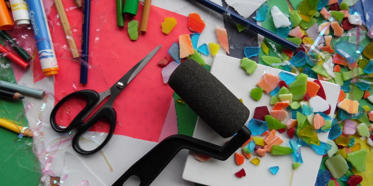 Colorful craft supplies including scissors, crayons, and a roller on a creative workspace.