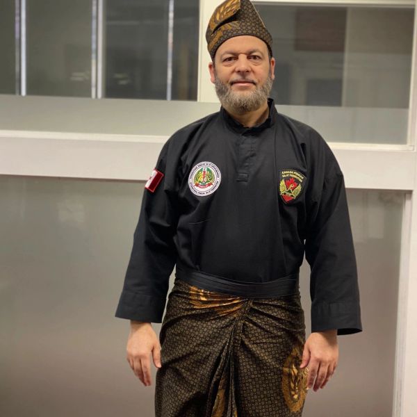 Man dressed in traditional attire with a black shirt and patterned sarong.