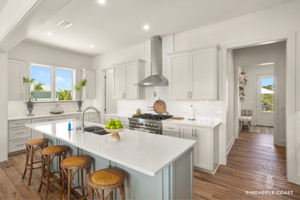 Bright modern kitchen with white cabinetry and wooden stools at the island.